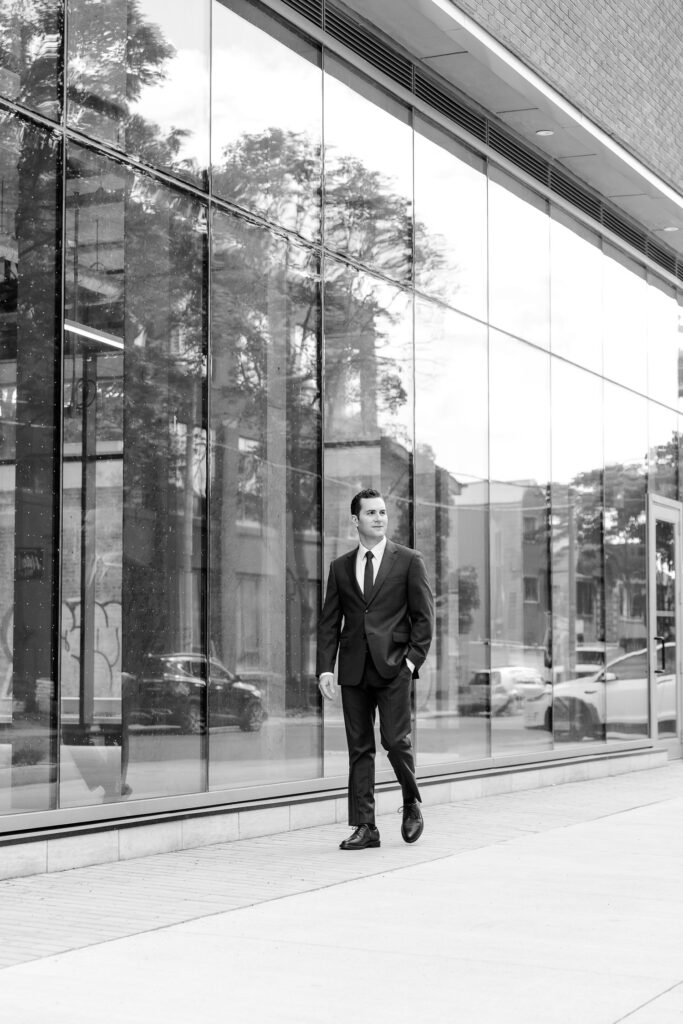 a man in a suit walking on a sidewalk