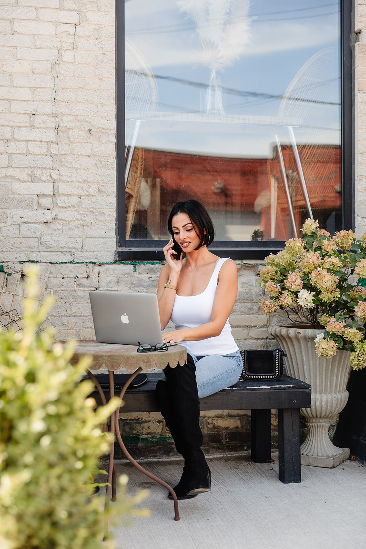 branding session for a matchmaker sitting on a bench with a laptop and phone